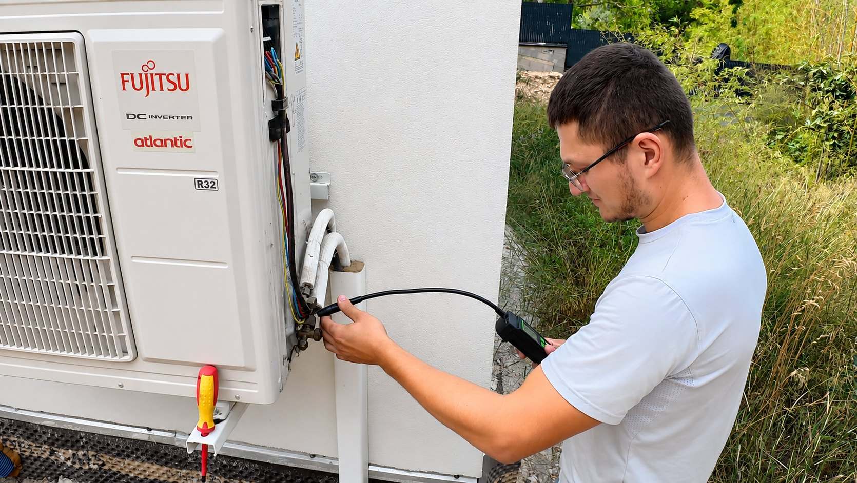 Technicien Nova’Clim relevant une mesure au manifold sur un groupe extérieur ouvert, tournevis isolé posé sur le châssis.